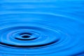 Splash drop of water with diverging water circles, on blue background Royalty Free Stock Photo