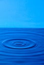 Splash drop of water with diverging water circles, on blue background Royalty Free Stock Photo