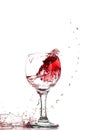 Splash of falling red wine in a round glass on a white background Royalty Free Stock Photo