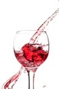 Splash of falling red wine in a round glass on a white background Royalty Free Stock Photo