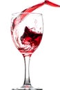 Splash of falling red wine in a round glass on a white background Royalty Free Stock Photo