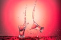 Splash in a flying wineglass with water or vodka on a red gradient background