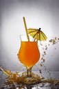 Splash in glass of orange alcoholic tropical cocktail drink with umbrella and straw Royalty Free Stock Photo