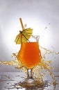 Splash in glass of orange alcoholic tropical cocktail drink with umbrella and straw Royalty Free Stock Photo