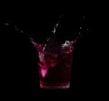 Splash from ice cube in a glass of red water or drink Royalty Free Stock Photo