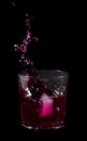 Splash from ice cube in a glass of red water or drink Royalty Free Stock Photo