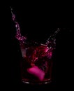 Splash from ice cube in a glass of red water or drink Royalty Free Stock Photo