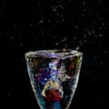 splash of liquid in rainbow sparkling glass with cherries on black background, low key Royalty Free Stock Photo