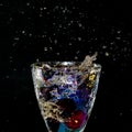 splash of liquid in rainbow sparkling glass with cherries on black background, low key Royalty Free Stock Photo