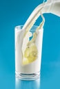 Splash of milk in transparent glass on blue background Royalty Free Stock Photo