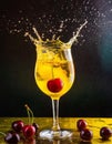 Splash of red cherries in a glass with colorful aperitif