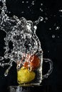Splash of red tomato and yellow lemon dive into glass of water with black background Royalty Free Stock Photo