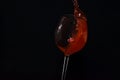 Splash of red wine in a glass on a black background. A glass of wine falls and spills. Royalty Free Stock Photo