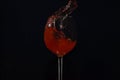 Splash of red wine in a glass on a black background. A glass of wine falls. Royalty Free Stock Photo