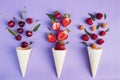 Splash of summer berries from ice cream cones on purple background. Summer time food flat lay Royalty Free Stock Photo