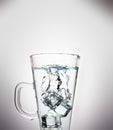 The splash of water in a clear glass is caused by ice cubes falling into the glass Royalty Free Stock Photo