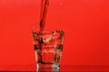 Splash of water in glass for whiskey on red background, copy space. Royalty Free Stock Photo