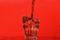 Splash of water in glass for whiskey on red background, copy space. Royalty Free Stock Photo