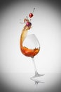 Splashed wine with cherry in the wineglass. Royalty Free Stock Photo