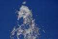 Splashes of flying water from the fountain against the blue sky Royalty Free Stock Photo