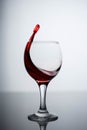 Splashes of red wine in a glass on a black glossy glass on a white background Royalty Free Stock Photo