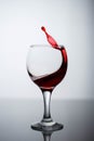 Splashes of red wine in a glass on a black glossy glass on a white background Royalty Free Stock Photo