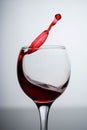 Splashes of red wine in a glass on a black glossy glass on a white background Royalty Free Stock Photo