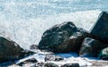 Splashes of sea waves on the black stones on the sand of the beach Royalty Free Stock Photo