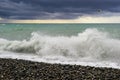 Splashes of waves during stormy wind in the sea at pebble beach.