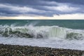 Splashes of waves during stormy wind in the sea at pebble beach.