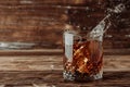 Splashes in a whiskey glass on a wooden background Royalty Free Stock Photo