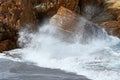 A big wave crashing into the rocks in the rough wild water of the ocean on a stormy during wintertime in South Africa. Royalty Free Stock Photo