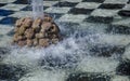 splashing fountain against the background of the bottom in the form of a chessboard