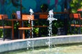 Splashing Of Fountain In The Garden Pond With Table And Chairs Of The Garden CafÃ© Royalty Free Stock Photo