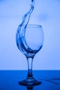 Splashing in a glass of clean drinking water on a black glass table on a blue background Royalty Free Stock Photo