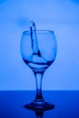 Splashing in a glass of clean drinking water on a black glass table on a blue background Royalty Free Stock Photo