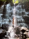 Splashing water at the waterfall and young woman traveller standing at the rock. Royalty Free Stock Photo