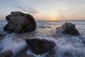 Splashing waves beat against the rocks on the beach at sunset Royalty Free Stock Photo
