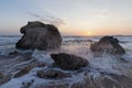 Splashing waves beat against the rocks on the beach at sunset Royalty Free Stock Photo