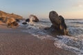 Splashing waves beat against the rocks on the beach at sunset Royalty Free Stock Photo
