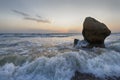Splashing waves beat against the rocks on the beach at sunset Royalty Free Stock Photo