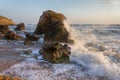 Splashing waves beat against the rocks on the beach at sunset Royalty Free Stock Photo