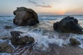 Splashing waves beat against the rocks on the beach at sunset Royalty Free Stock Photo