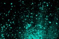 A splatter of green blue colored pigment powder on black background