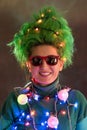 Splended girl with green hair dressed in Christmas garlands. A girl is depicting a Christmas tree. The concept of a good mood on a Royalty Free Stock Photo