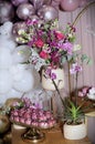 Beautiful arrangement of various flowers, orchid and rose-shaped sweets and white balloons decorating birthday table Royalty Free Stock Photo