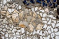 Splinters of a white ceramic tile on cement. Texture white pieces against a dark background. White mosaic on the wall texture