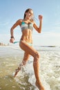 Splish splash. an attractive young woman running on the beach.