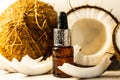 Split coconuts with coconut essential oil. Coconut serum for the face. A bottle of whey oil with a pipette on a white-beige Royalty Free Stock Photo