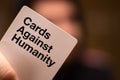 Split,Croatia April 2020 Dark blurred out of focus man in the background holding a white cards against humanity card, card filling Royalty Free Stock Photo